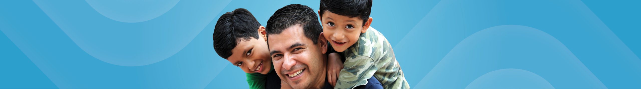 A man and two young boys smiling and hugging.